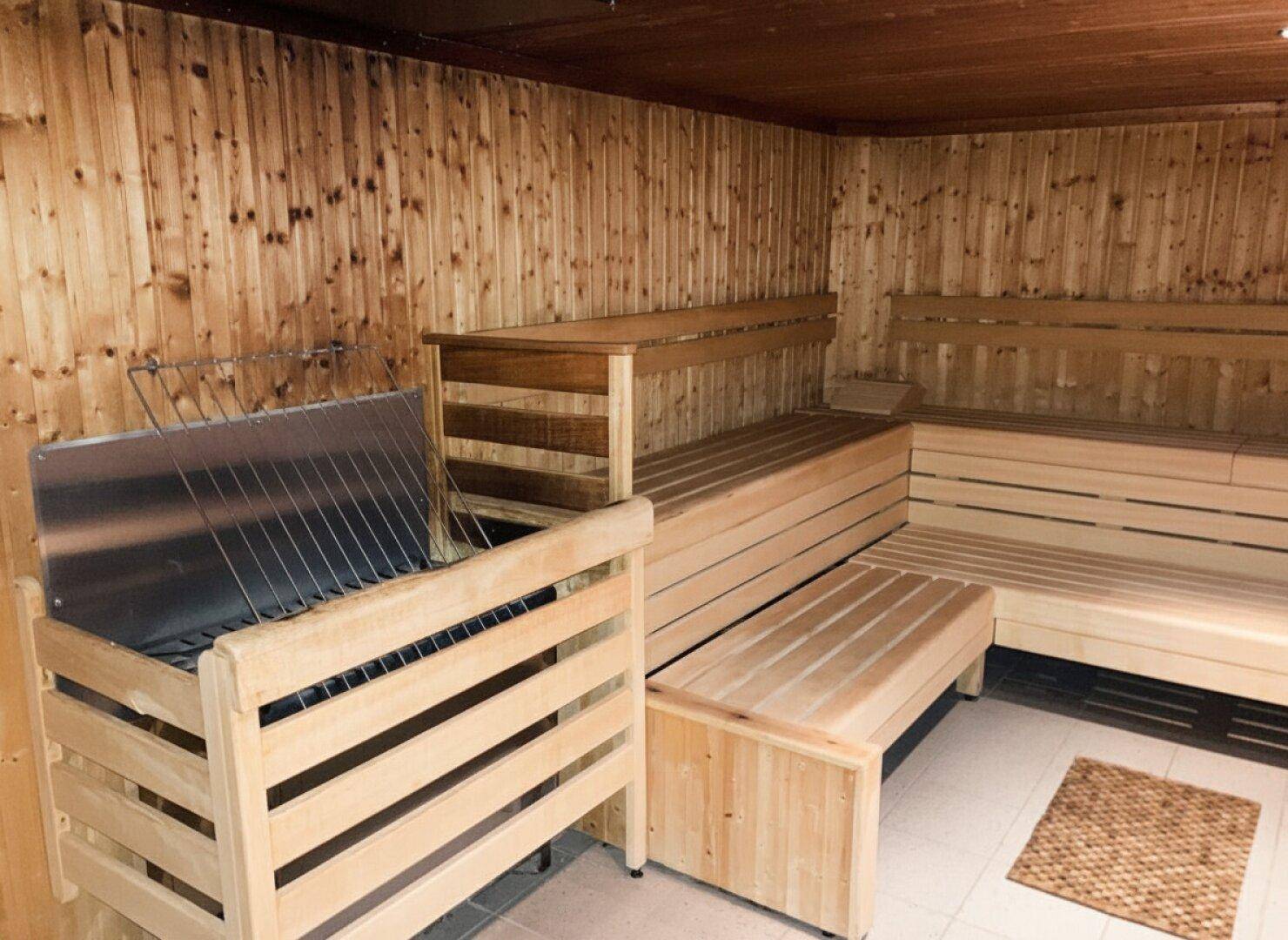 Geräumige Holzsauna mit mehreren Bänken und traditionellem Saunaofen für Entspannung.