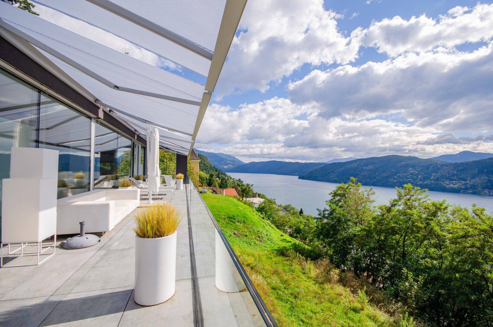 Weitläufige Terrasse mit modernen Loungemöbeln und spektakulärem Blick auf den See und die Berge.