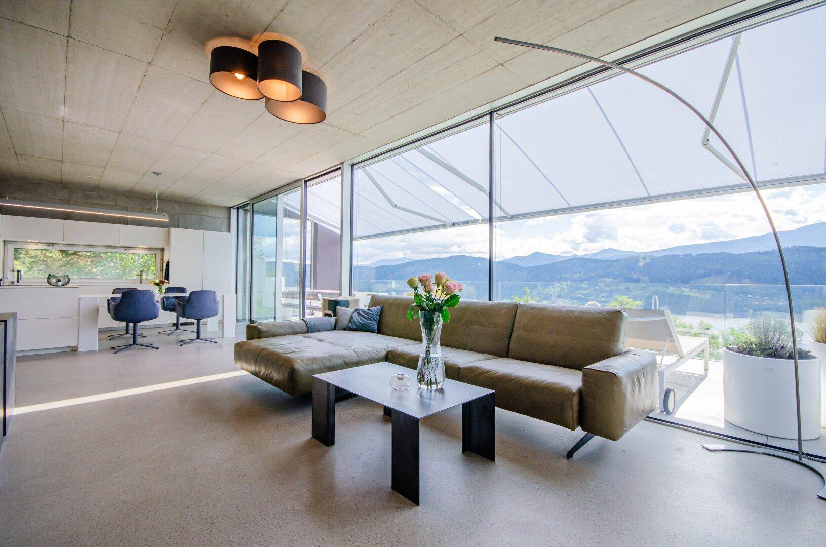 Geräumiges Wohnzimmer mit bequemer Eckcouch, modernen Leuchten und weitem Seeblick.