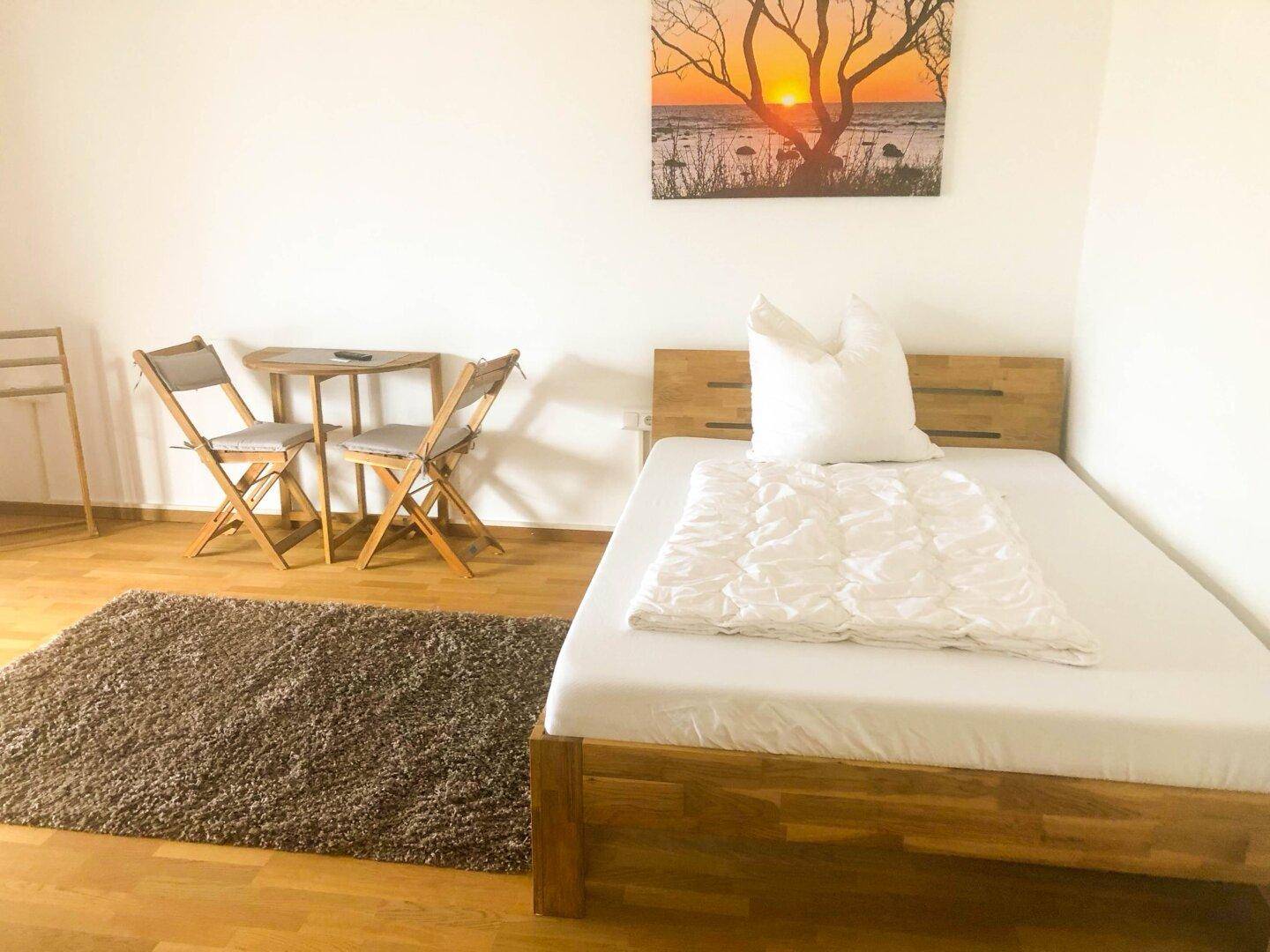 Gemütliches Schlafzimmer mit Holzbett, Parkettboden und einem kleinen Tisch für entspannte Momente.