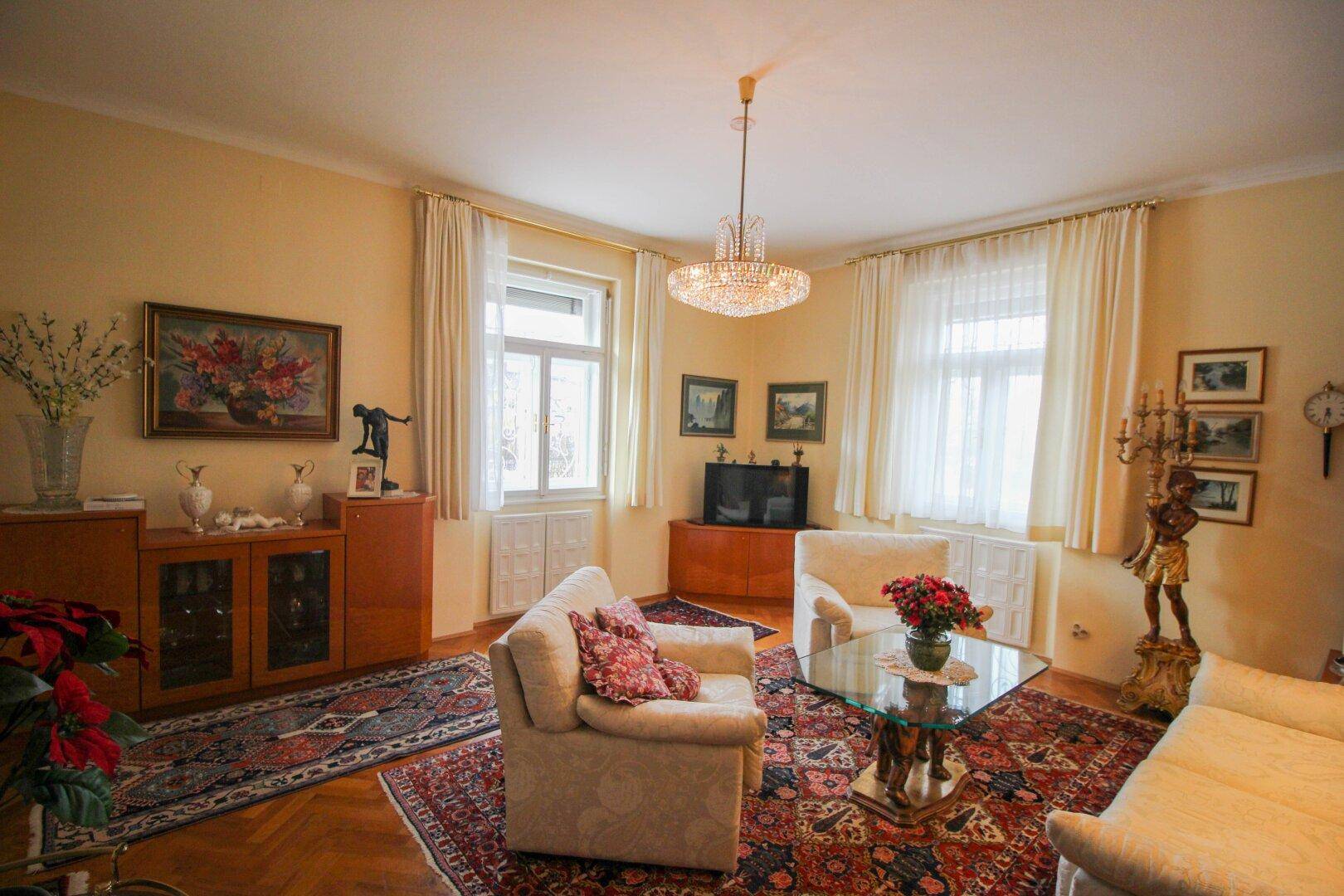 Gemütliches Wohnzimmer mit traditionellen Möbeln, Teppich und Kronleuchter.