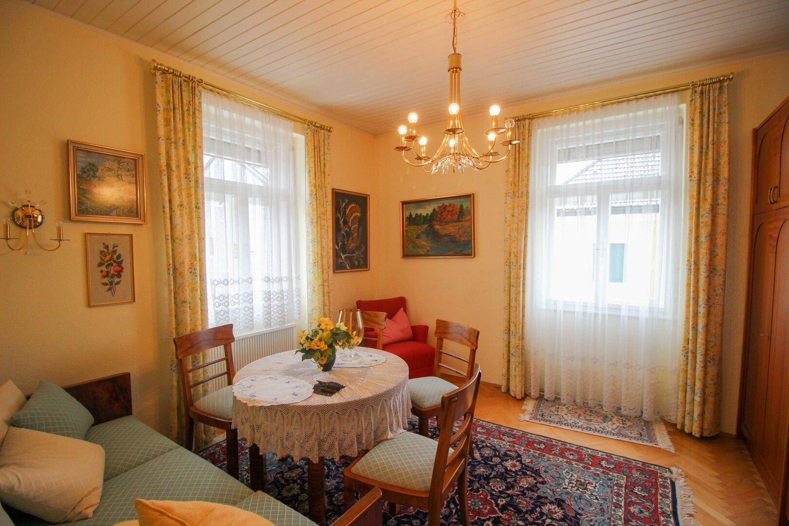 Heller Essbereich mit ovalem Tisch, traditionellen Stühlen und Kronleuchter.