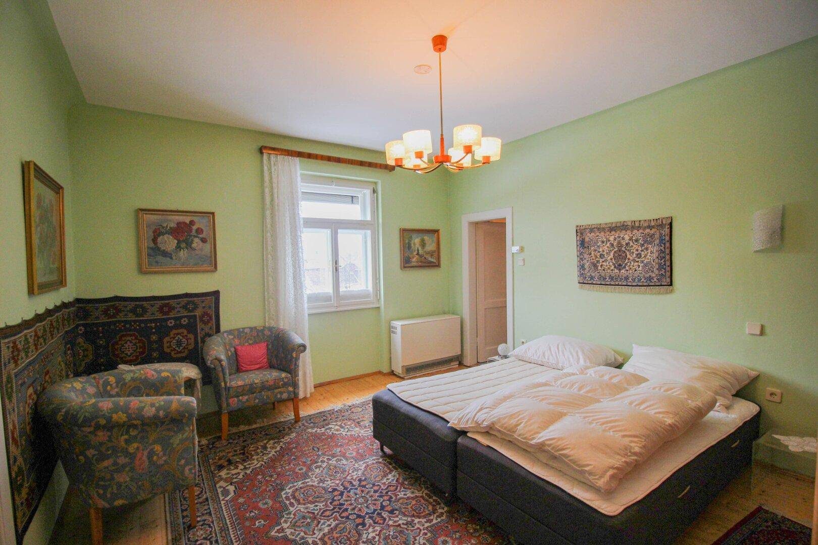 Schlafzimmer mit grünen Wänden, zwei Einzelbetten und traditionellen Teppichen.