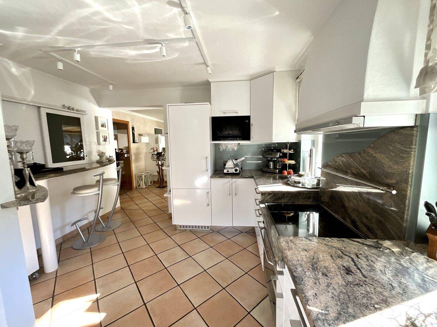 Moderne Küche mit weißen Schränken, Granitarbeitsplatten und integrierter Frühstücksbar.
