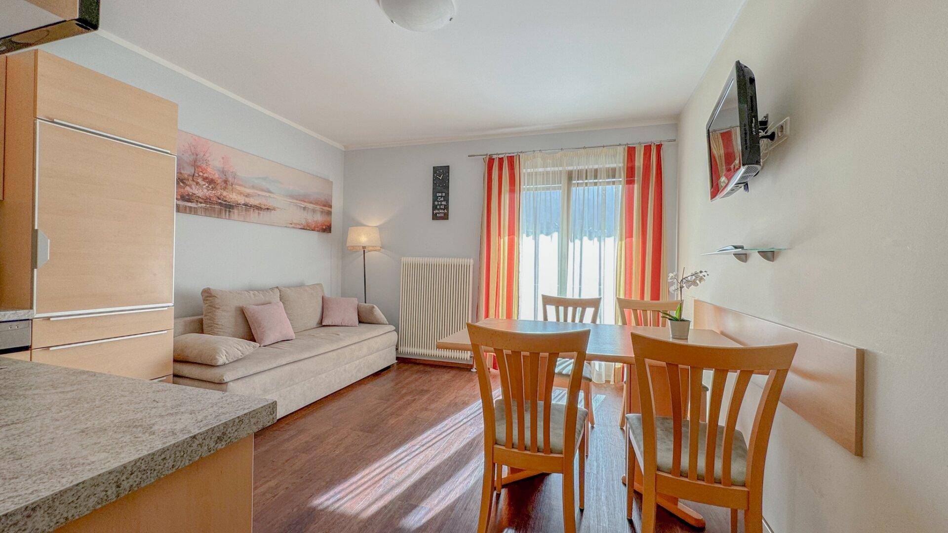 Heller Wohn-Essbereich mit Küchenzeile, Esstisch und Zugang zum Balkon.