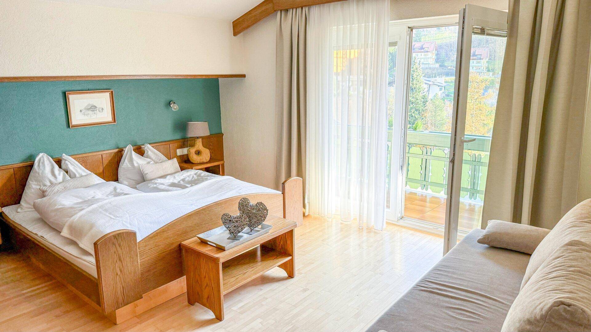 Gemütliches Schlafzimmer mit Doppelbett, Holzelementen und Balkonzugang.