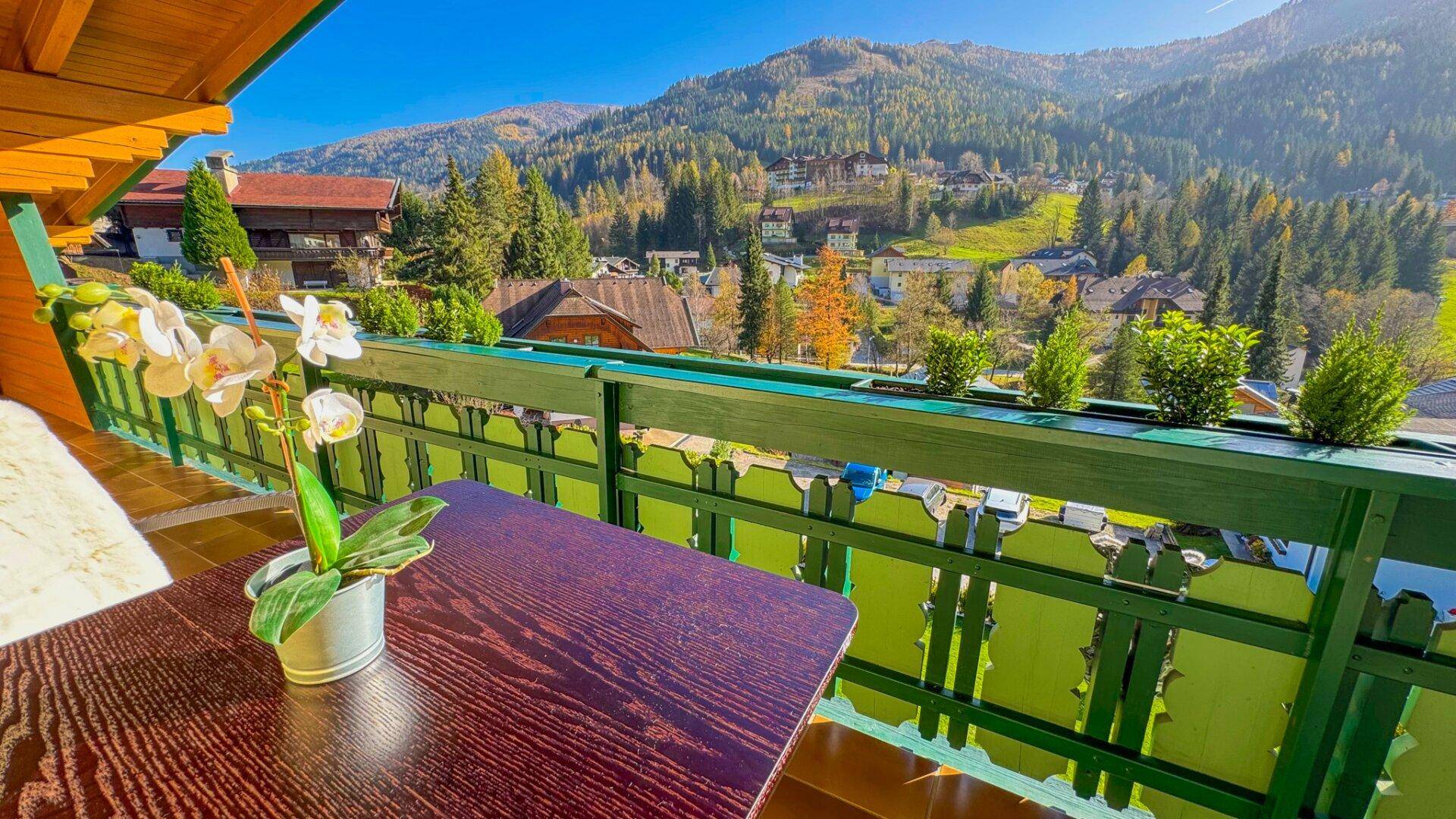 Gemütlicher Balkon mit Holzbalken und einem atemberaubenden Blick auf die umliegende Berglandschaft.