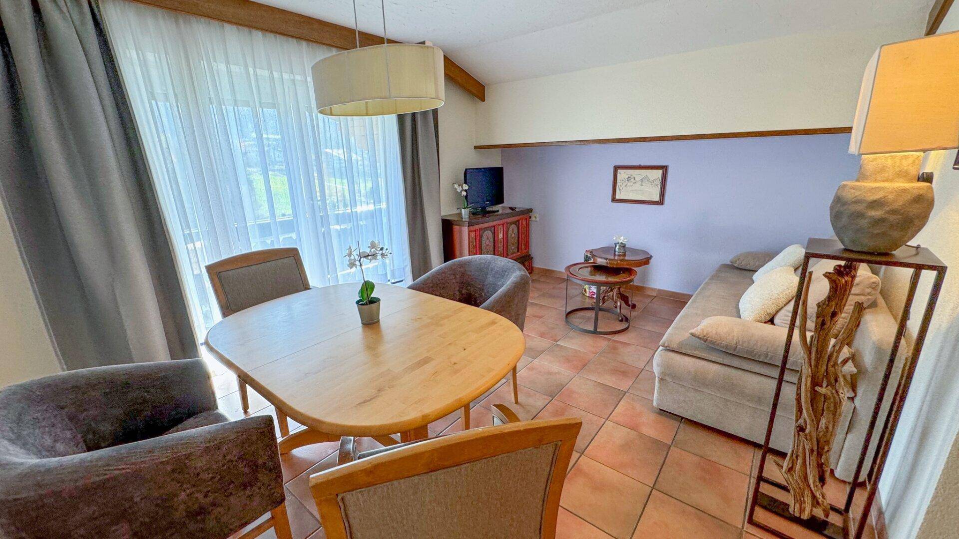 Gemütlicher Wohn-Essbereich mit Holztisch, bequemen Sofas und Zugang zum Außenbereich.