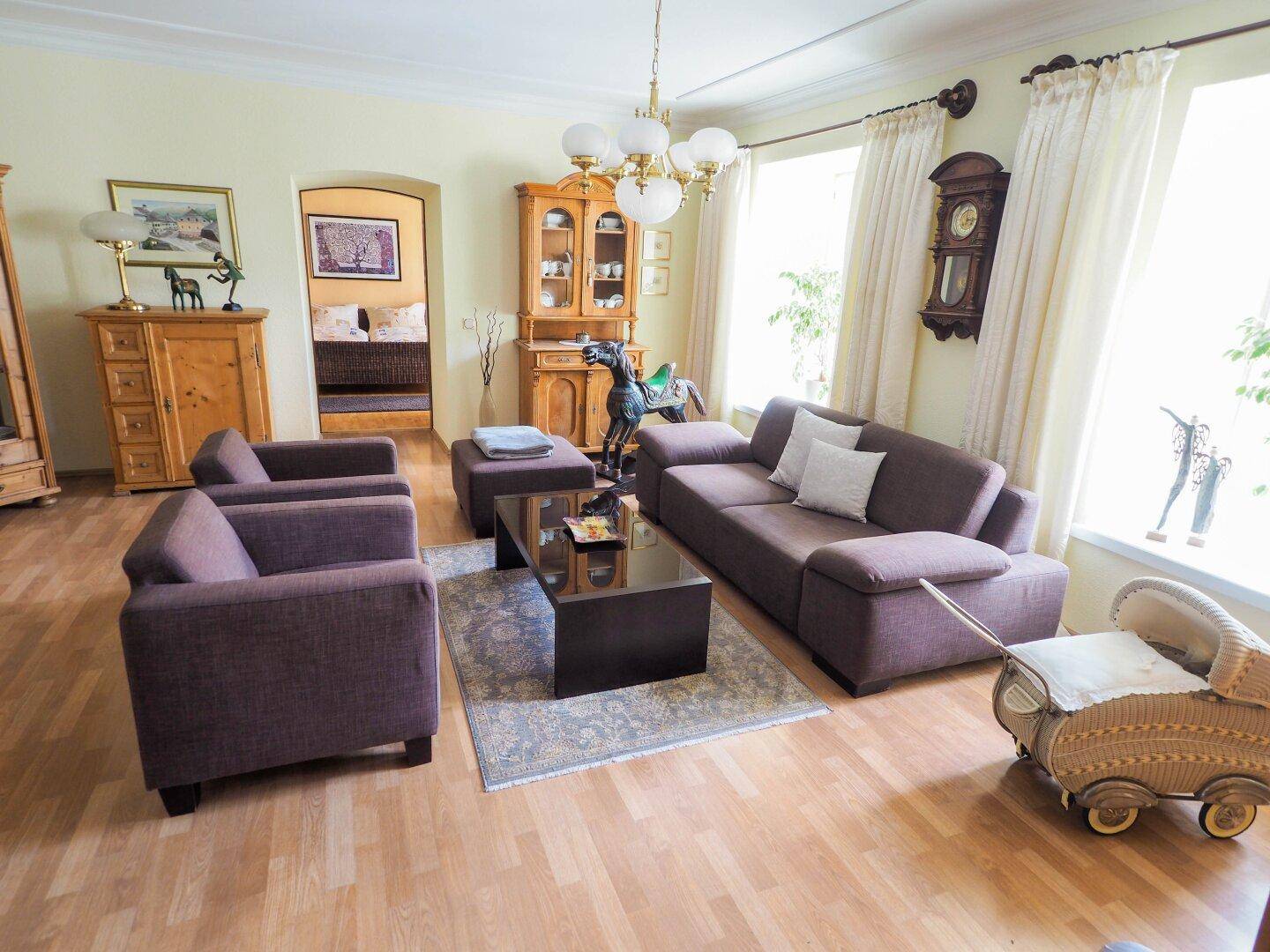 Gemütliches Wohnzimmer mit hellem Parkettboden, bequemen Sofas und traditionellen Holzmöbeln.