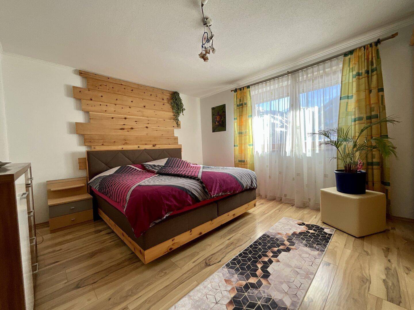 Helles Schlafzimmer mit Holzboden, Doppelbett und dekorativer Holzwand.