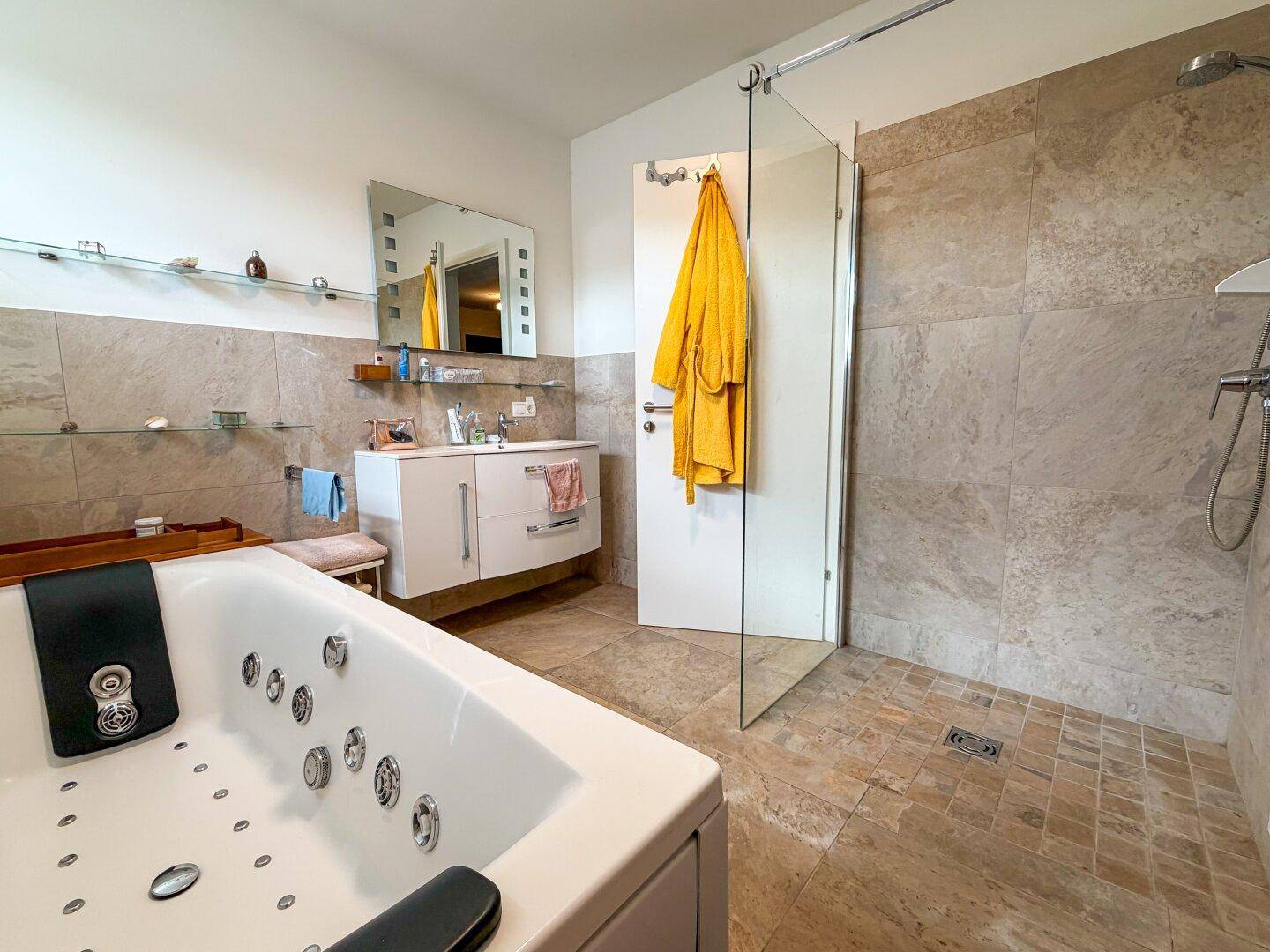 Modernes Badezimmer mit Whirlpool-Badewanne, ebenerdiger Dusche und großformatigen Fliesen.