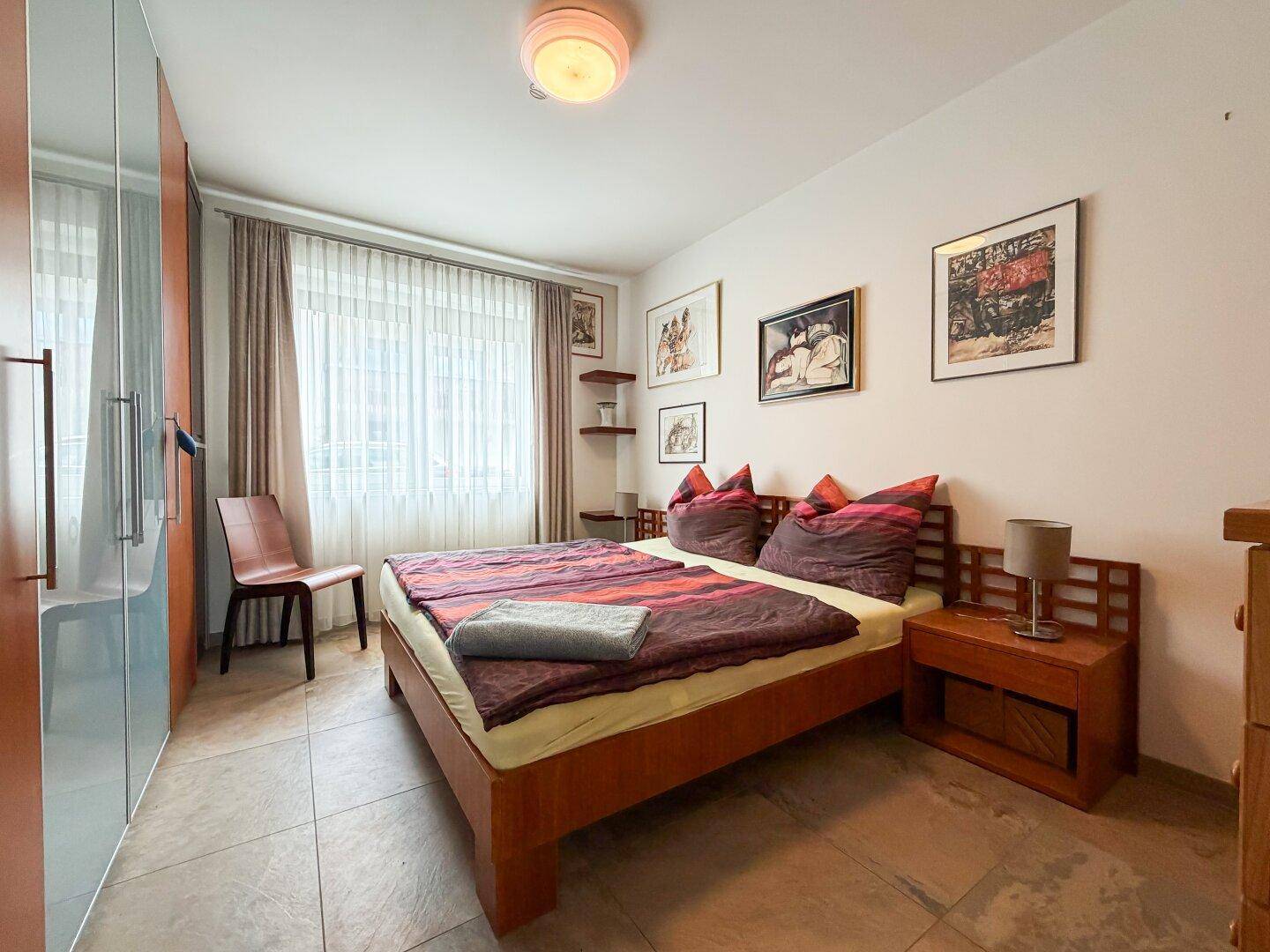 Gemütliches Schlafzimmer mit Doppelbett, Einbauschrank und Fliesenboden.