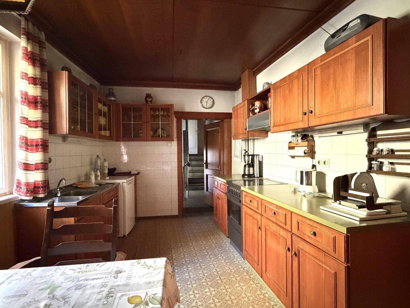 Traditionelle Küche mit Holzschränken, gefliestem Spritzschutz und einem gemusterten Fliesenboden.