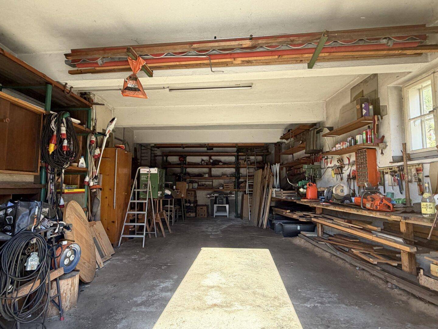 Geräumige Garage oder Werkstatt mit viel Stauraum, Werkzeugen und einem Betonboden.