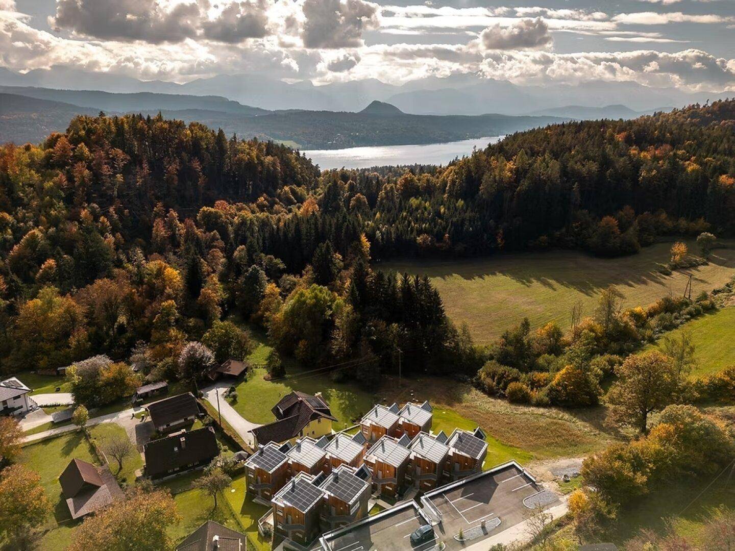 Weitläufiger Blick auf die Siedlung, den See und die umliegende Berglandschaft im Herbst.