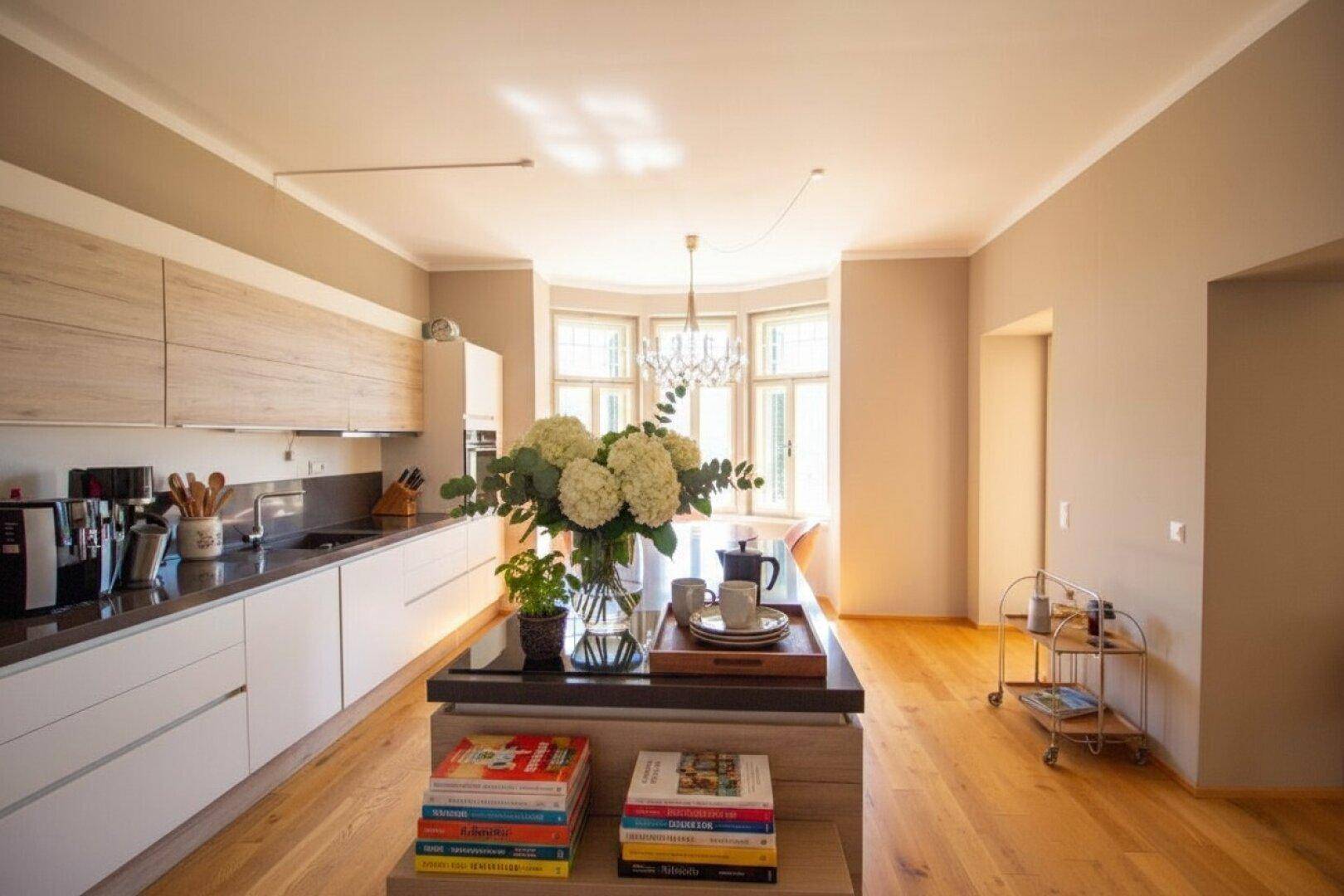 Moderne Küche mit Kücheninsel, hellen Schränken und einem Essbereich in der Erkerfensternische.