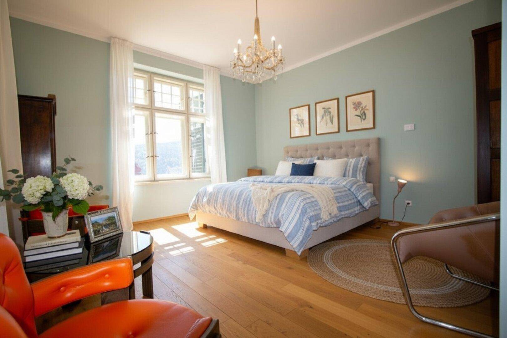 Ruhiges Schlafzimmer mit hellblauen Wänden, Holzboden und einem großen Fenster für viel Tageslicht.