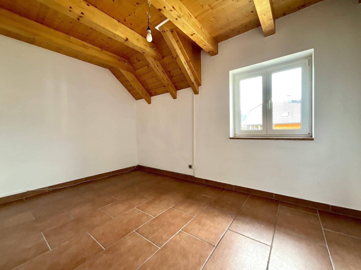 Helles Schlafzimmer mit Terrakottafliesen, weiß gestrichenen Wänden und sichtbarer Holzbalkendecke.