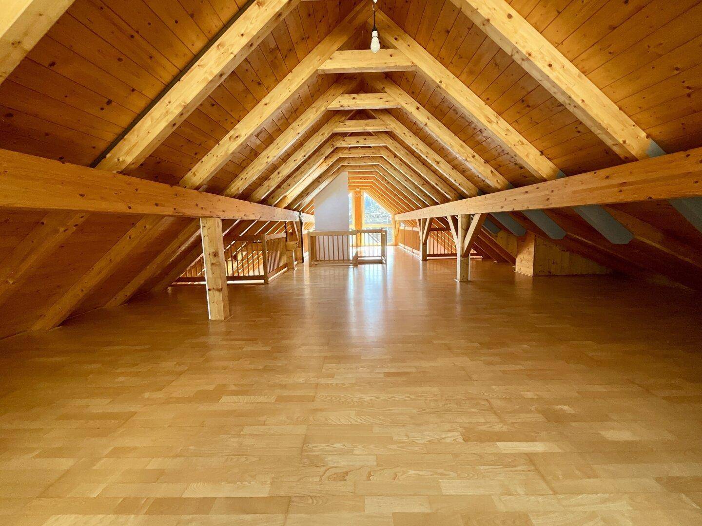Großer offener Dachbodenbereich mit Holzboden, sichtbaren Balken und viel Potenzial zur Gestaltung.