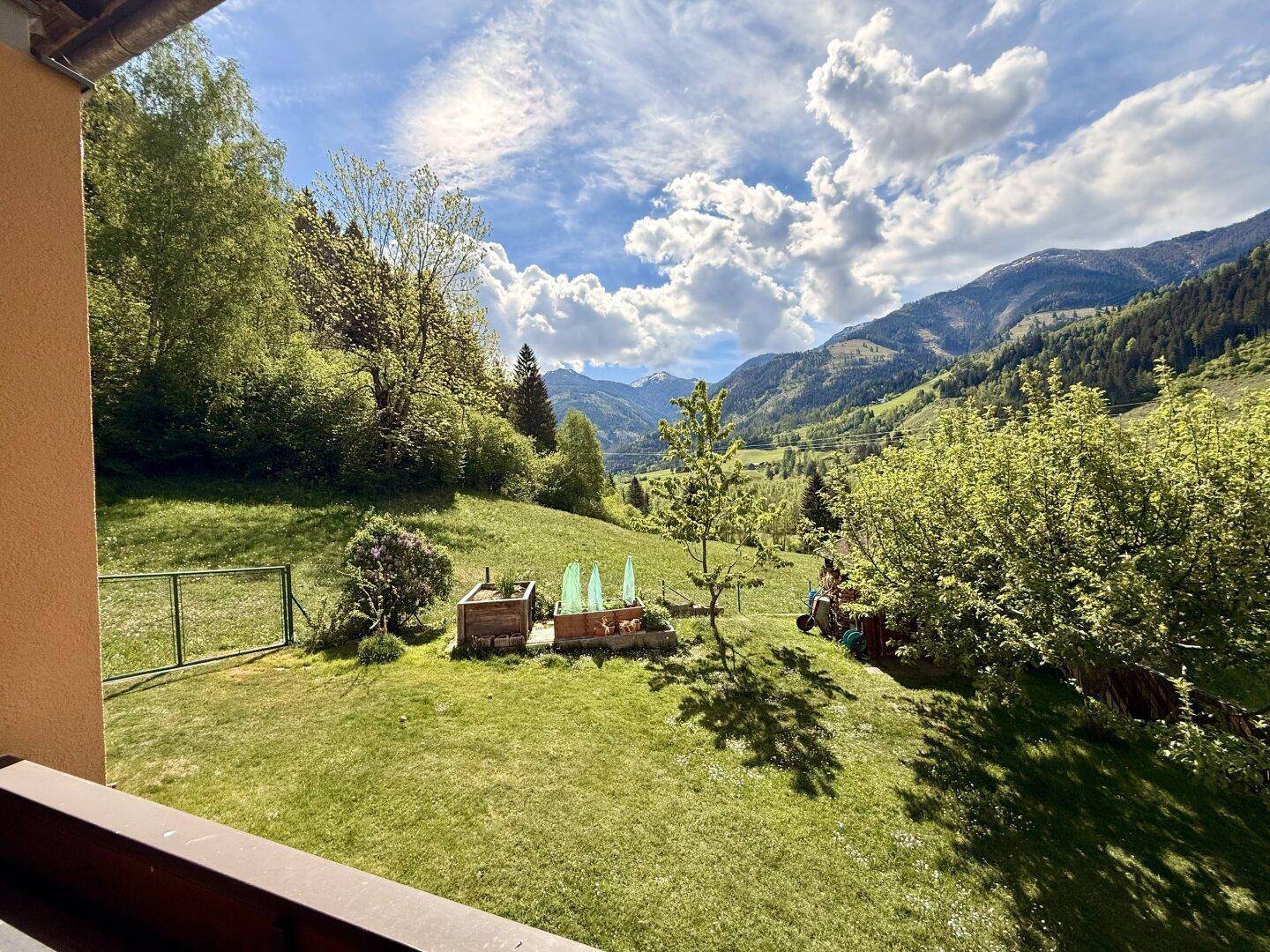 Weitläufiger Garten mit Rasenfläche und atemberaubendem Blick auf die Alpenlandschaft.