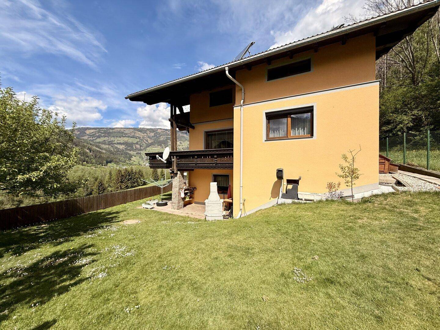 Seitenansicht des Hauses mit gepflegtem Rasen und einem Grillplatz im Freien.