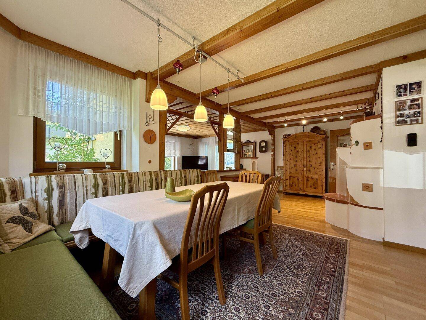 Gemütlicher Essbereich im alpinen Stil mit Holzbalkendecke und traditionellem Kachelofen.