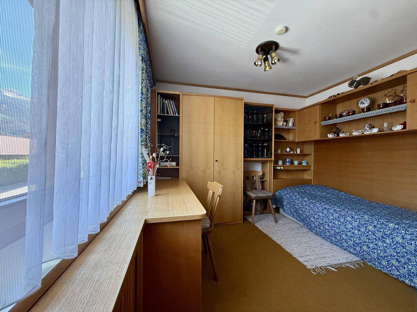 Kleines Schlafzimmer oder Arbeitszimmer mit Einzelbett, Einbauschränken und Schreibtisch.