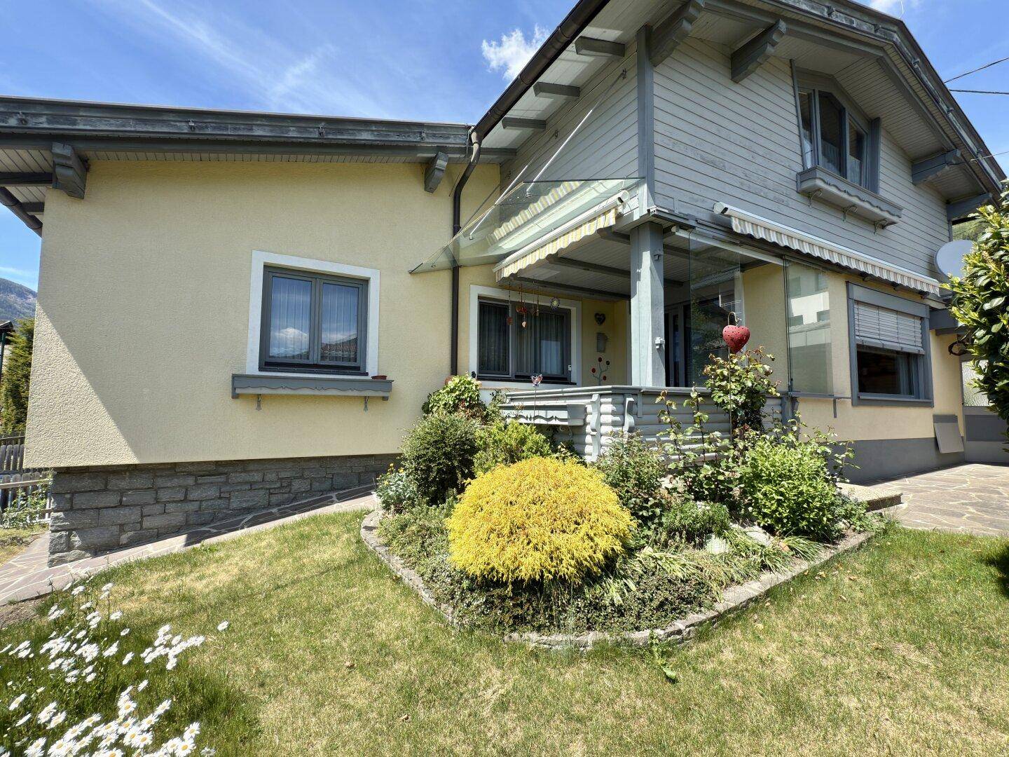 Eingangsbereich des Hauses mit überdachtem Vorbau und dekorativen Sträuchern im Vorgarten.