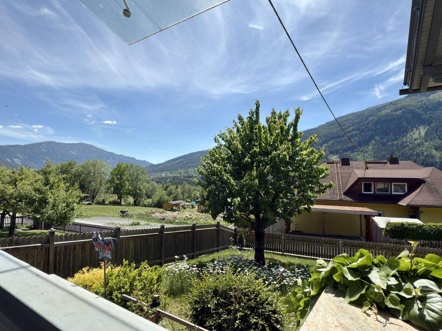 Panoramablick auf die umliegende Berglandschaft und grüne Täler von einem Balkon aus.
