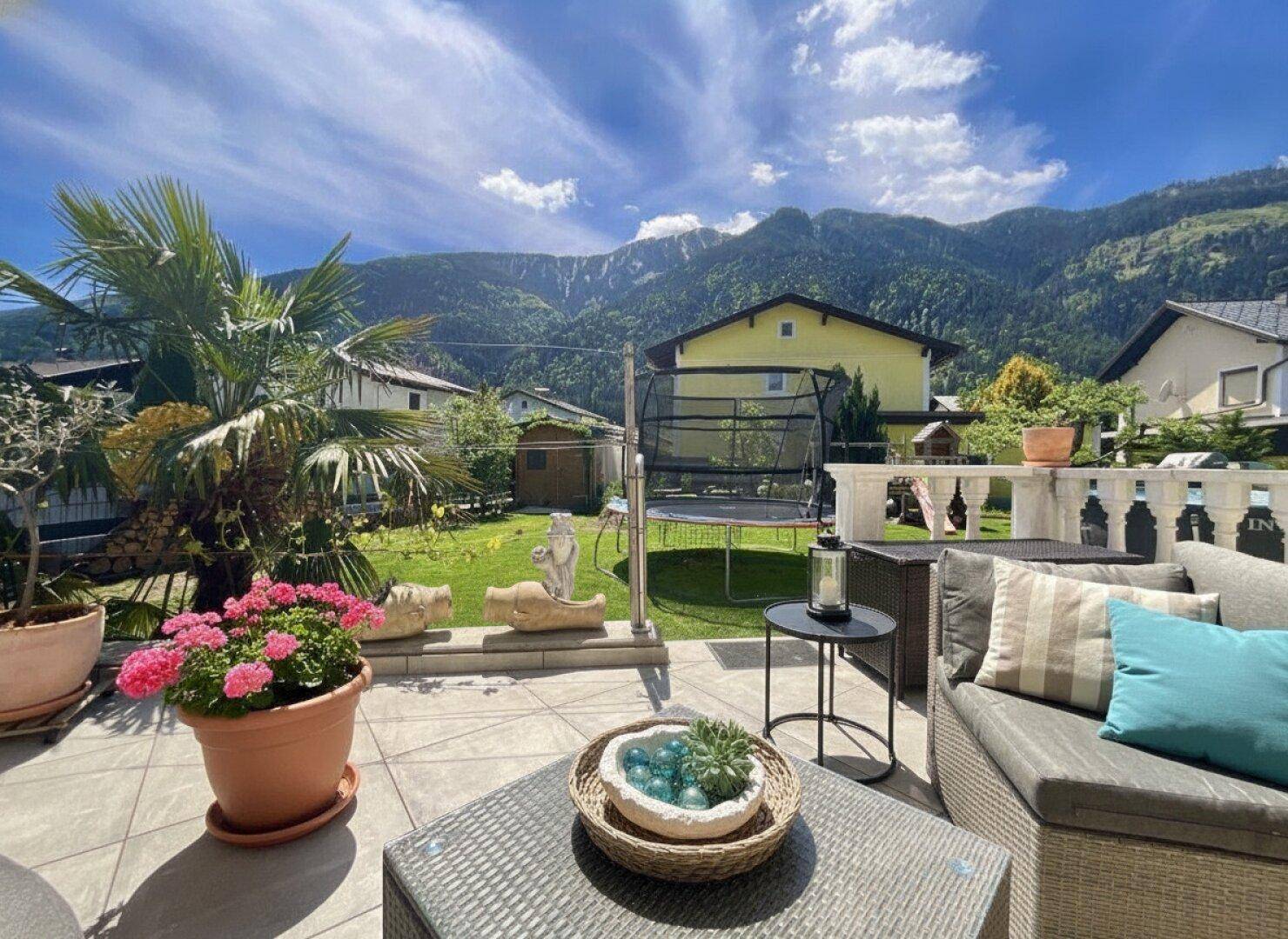 Gemütliche Terrasse mit Sitzgelegenheiten, Palmen und weitem Blick auf die Berge.