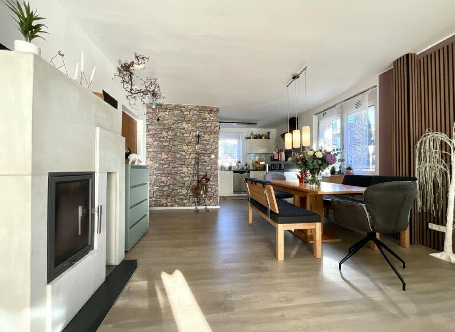 Großzügiger Wohn-Essbereich mit Kamin, Holzboden und moderner Einrichtung.