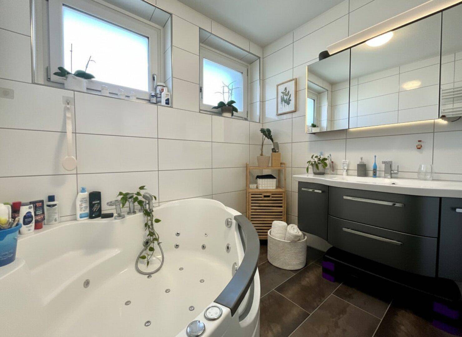 Geräumiges Badezimmer mit Eck-Whirlpool, Doppelwaschbecken und Fenster.