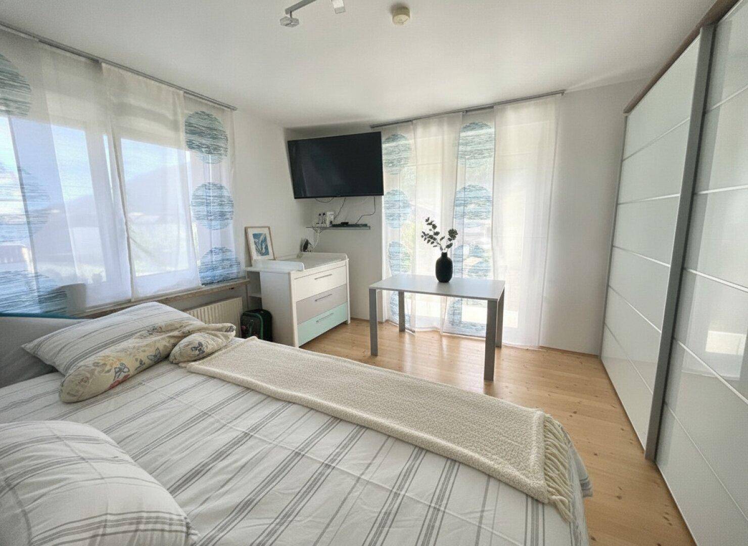 Helles Schlafzimmer mit großem Bett, Einbauschrank und Fenstern mit weitem Ausblick.