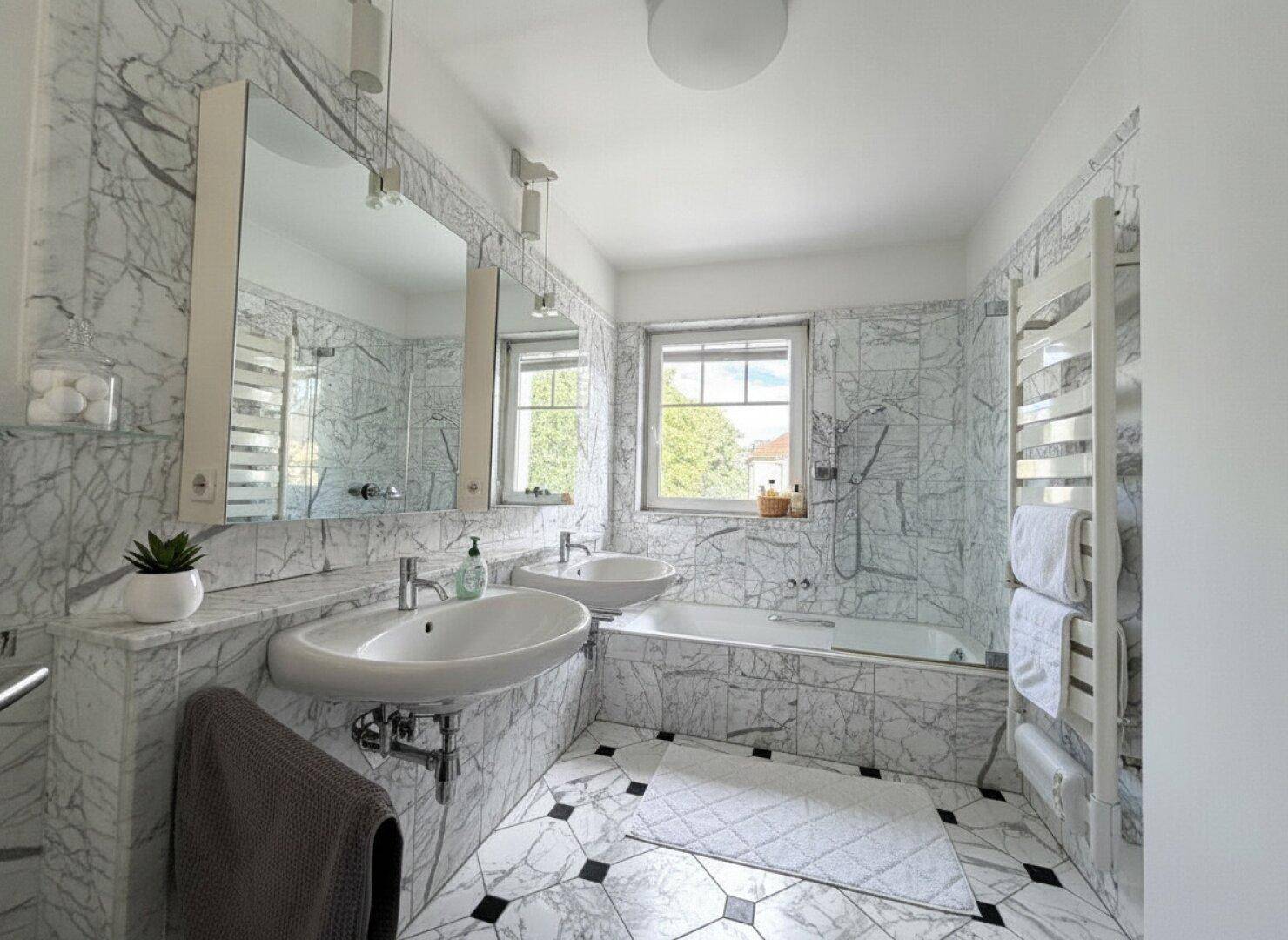 Elegantes Badezimmer mit Marmorfliesen, Doppelwaschbecken, Badewanne und Fenster.