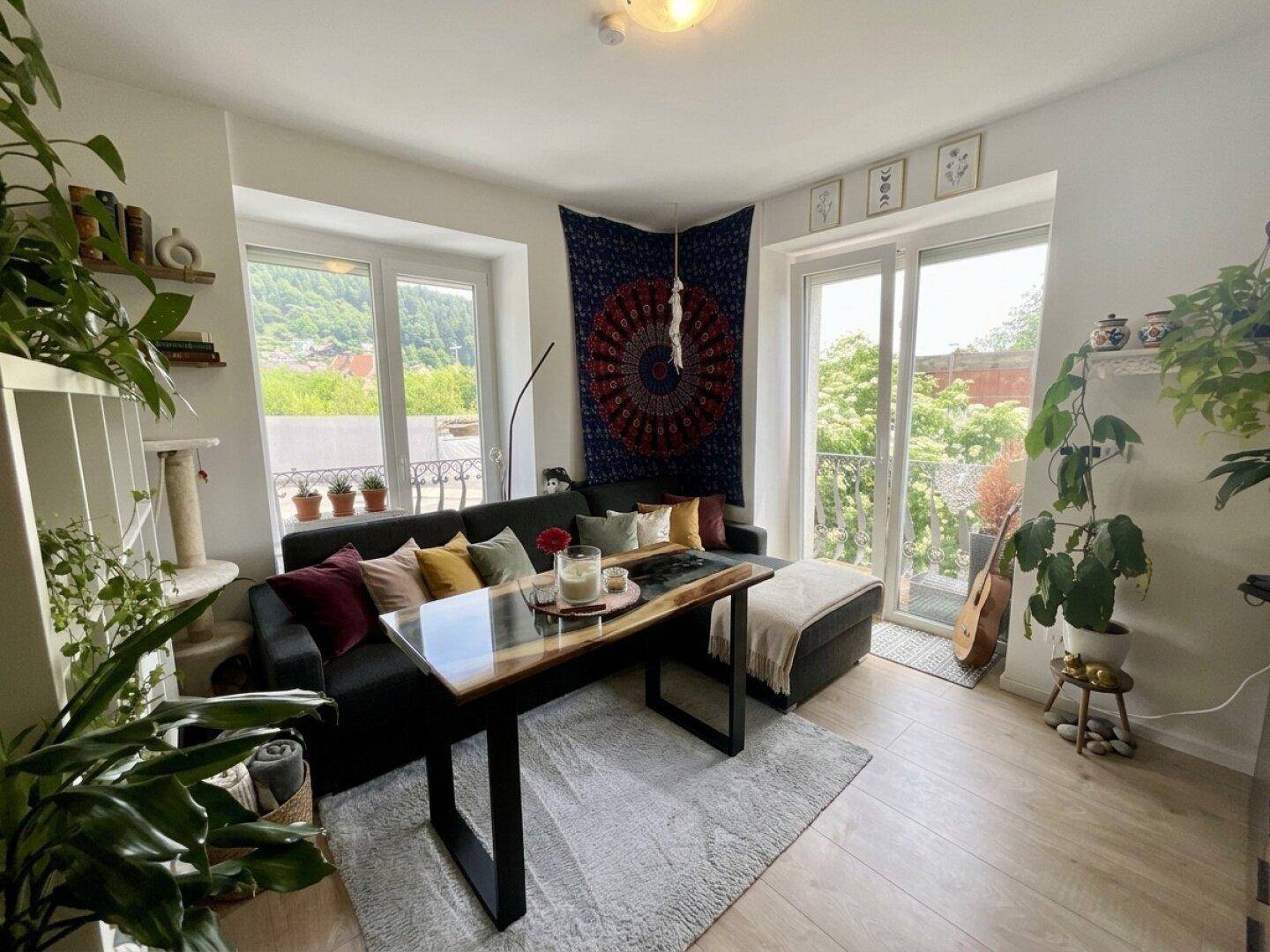 Helles Wohnzimmer mit Balkonzugang, Sofa und Blick ins Grüne.