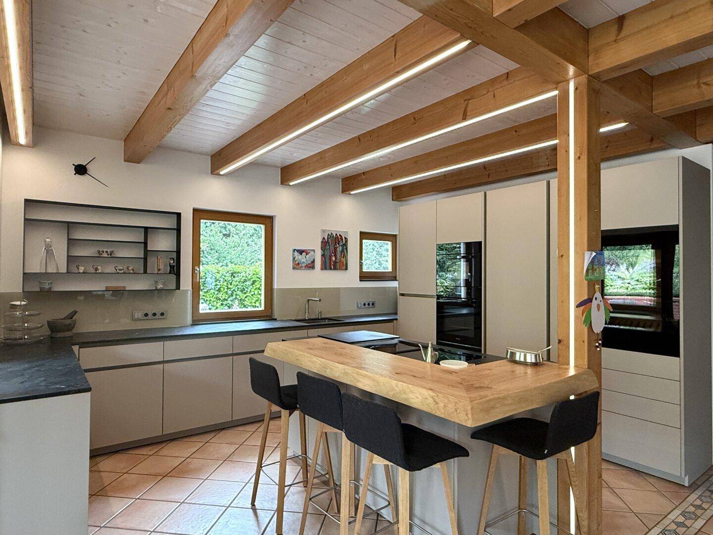 Moderne Küche mit Holzbalken, Kücheninsel und integrierten Geräten, ideal für geselliges Kochen.