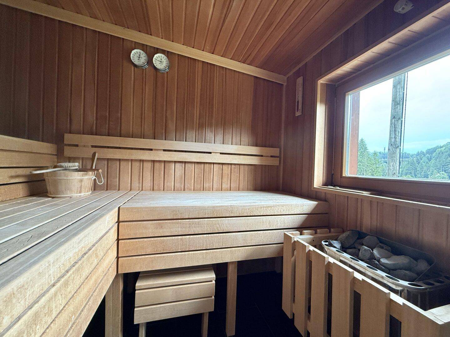 Holzvertäfelte Sauna mit Bänken und Ofen, ideal zur Entspannung.