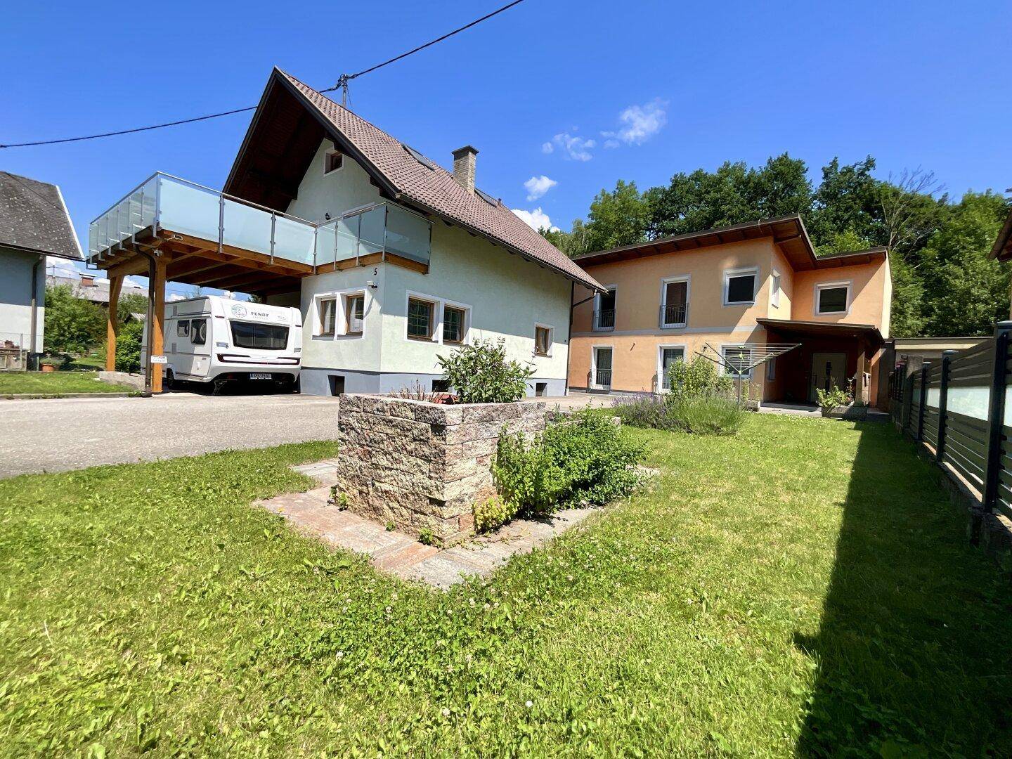 Gepflegter Gartenbereich mit Rasenfläche, Hochbeet und dem Haus im Hintergrund.