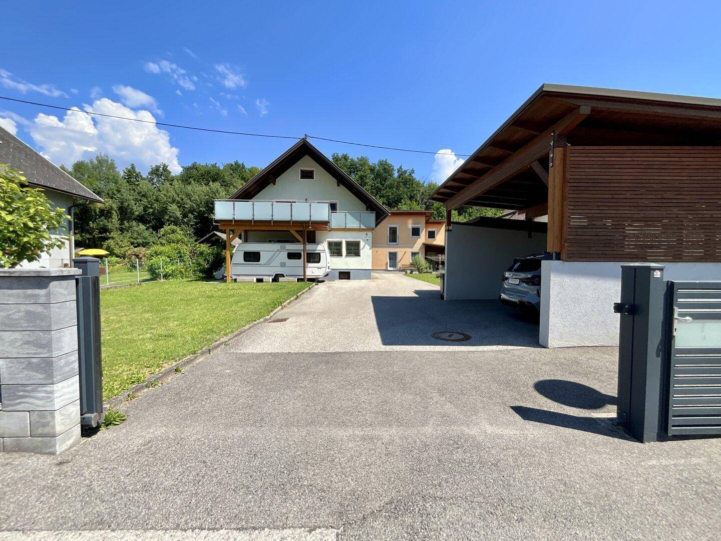 Einfahrt zum Haus mit Carport und Blick auf die umliegende Natur.