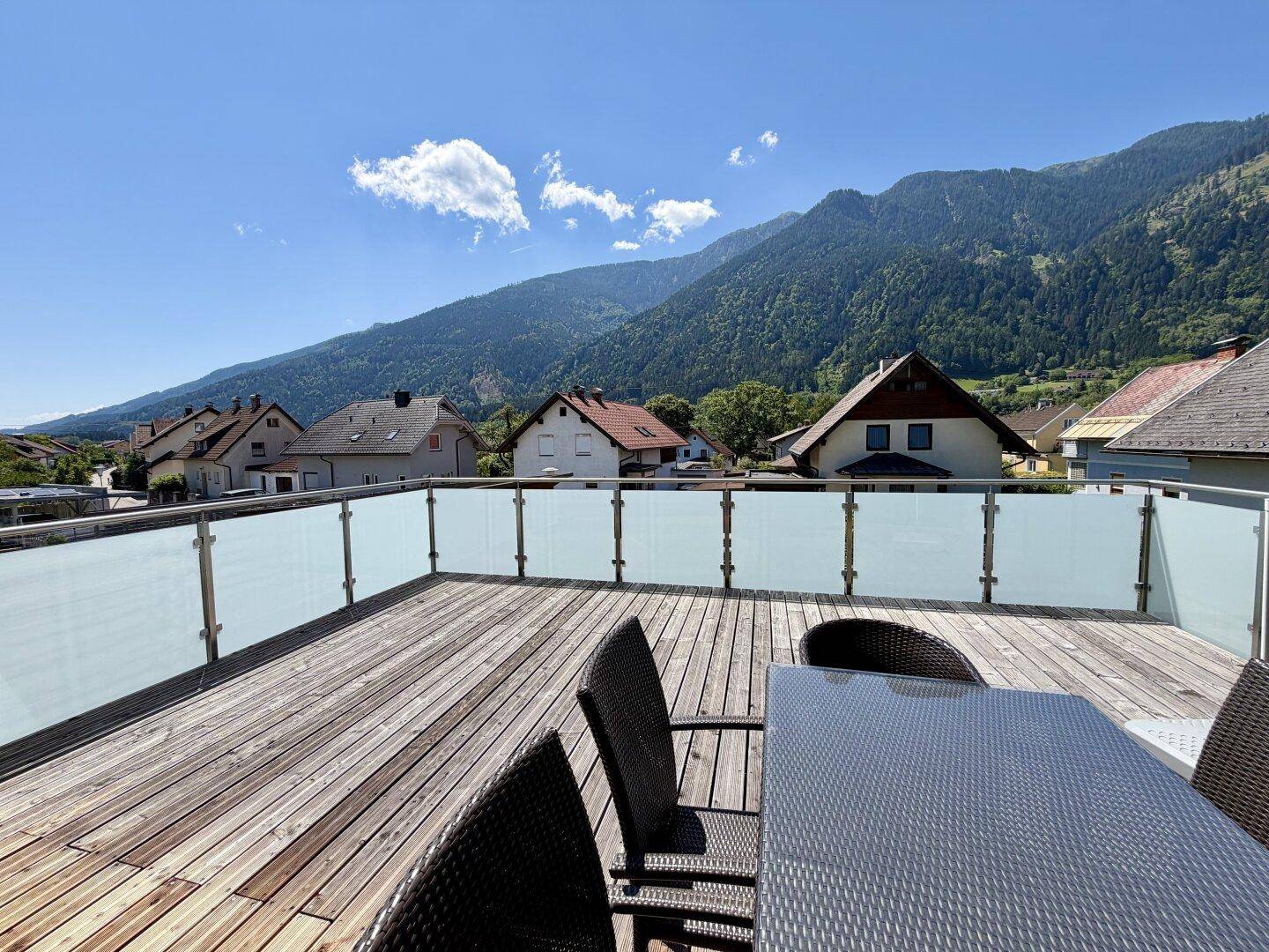 Großzügige Holzterrasse mit Glasgeländer und atemberaubendem Bergblick.
