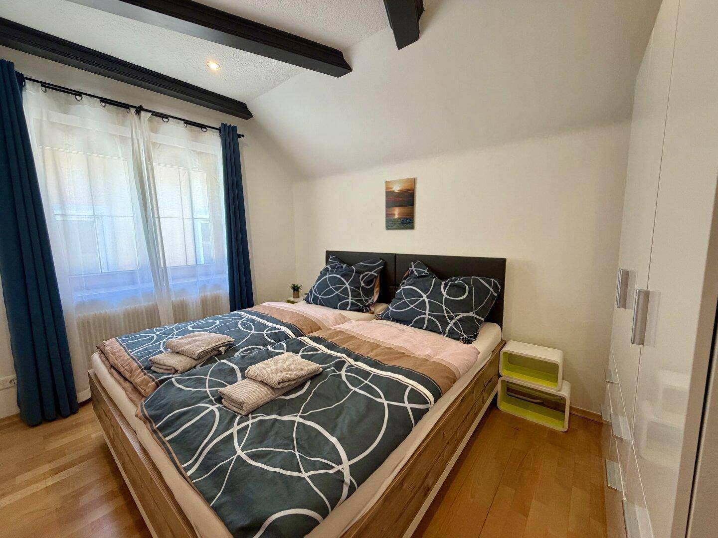 Helles Schlafzimmer mit Doppelbett, weißem Kleiderschrank und Holzboden.