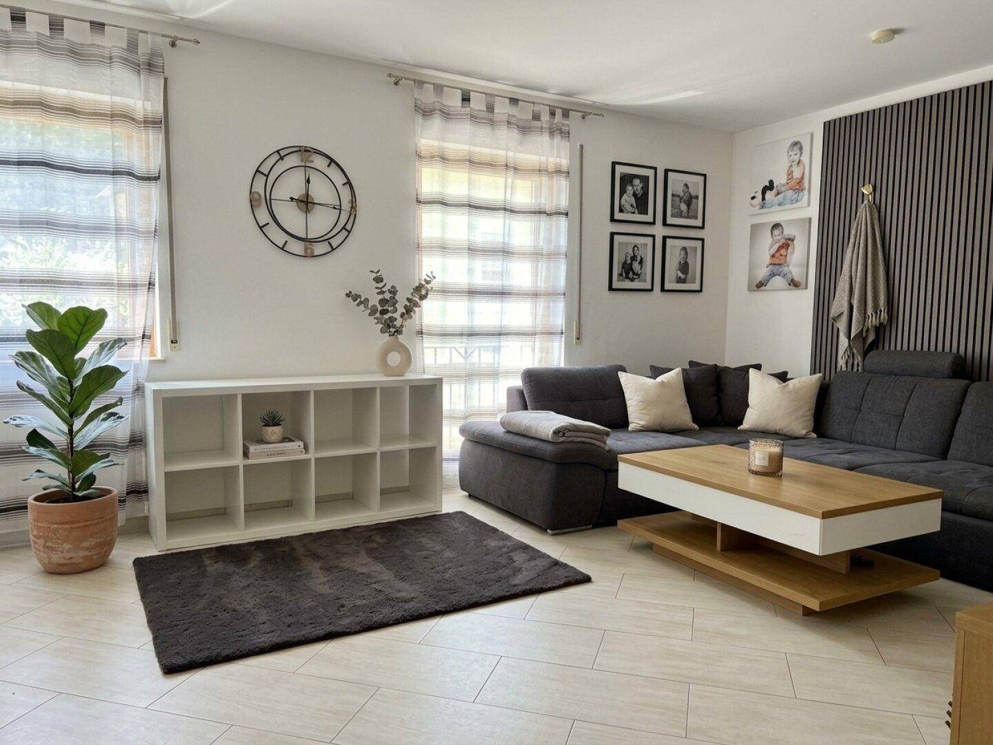 Modernes Wohnzimmer mit grauem Ecksofa, Couchtisch und hellen Fliesenboden.