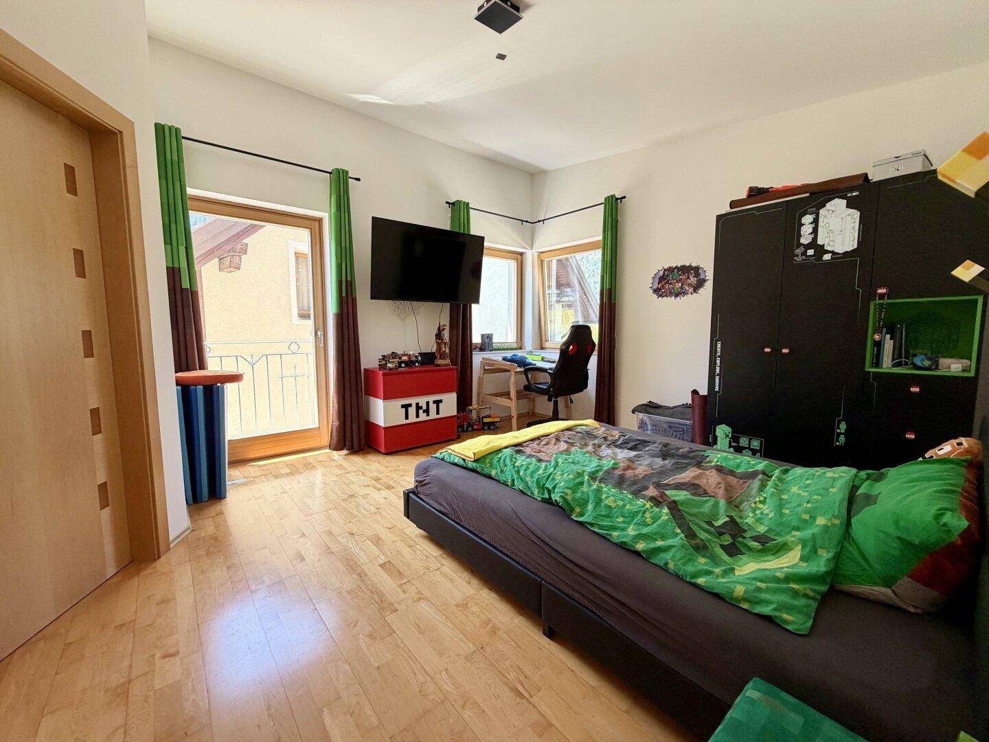 Kinderzimmer mit Bett, Schreibtisch, Kleiderschrank und Zugang zu einem Balkon.