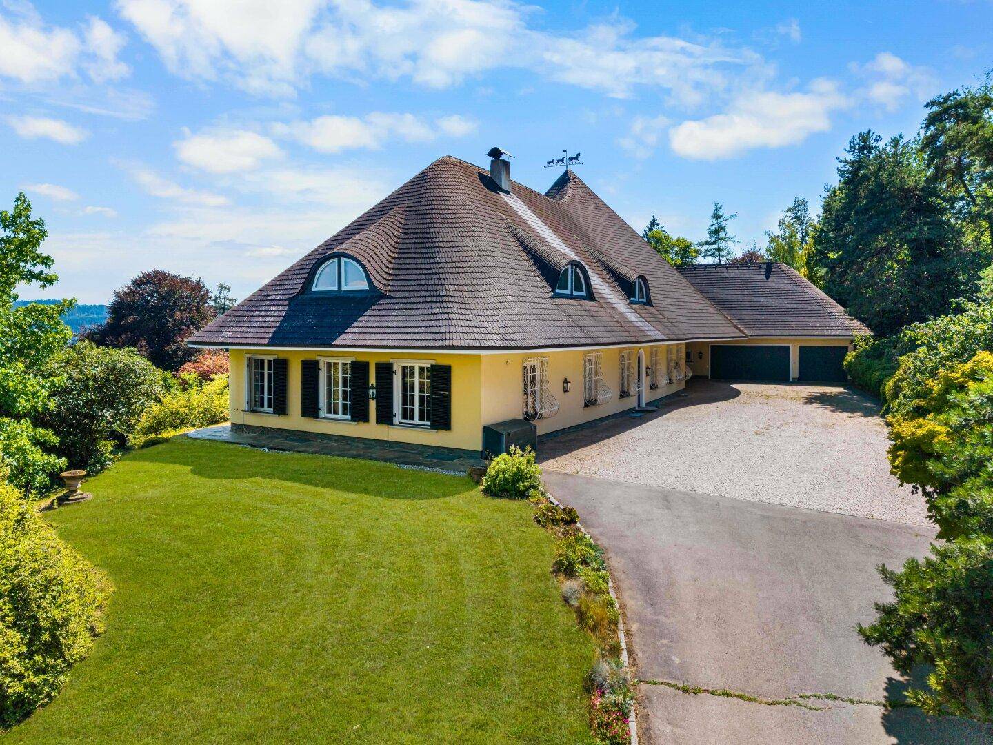 Elegantes Landhaus mit weitläufiger Auffahrt, gepflegtem Rasen und traditionellem Dach.