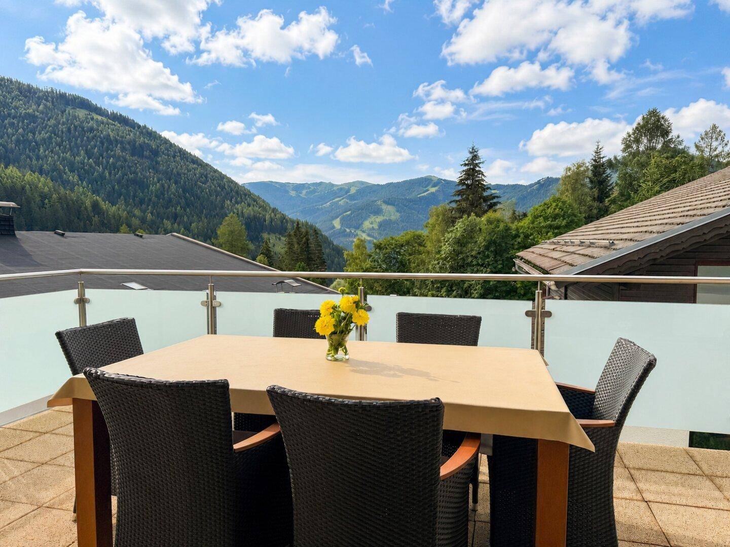 Geräumige Terrasse mit Esstisch und Stühlen, bietet einen weiten Blick auf die Berge.