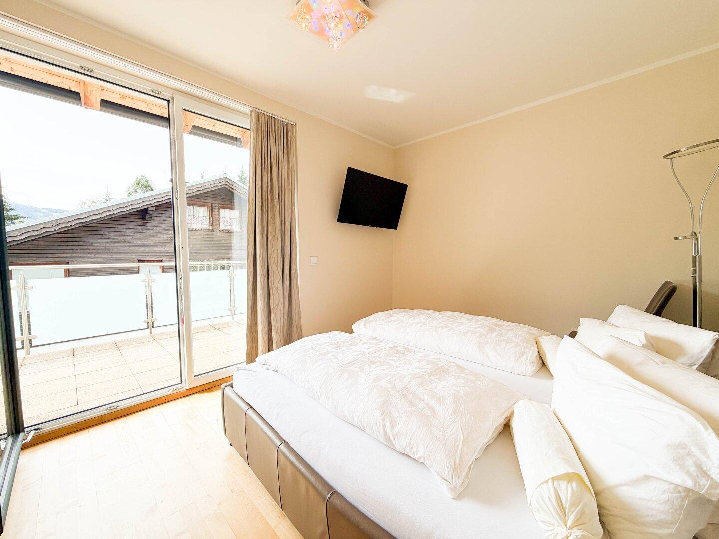 Gemütliches Schlafzimmer mit Doppelbett und direktem Zugang zu einem großen Balkon.