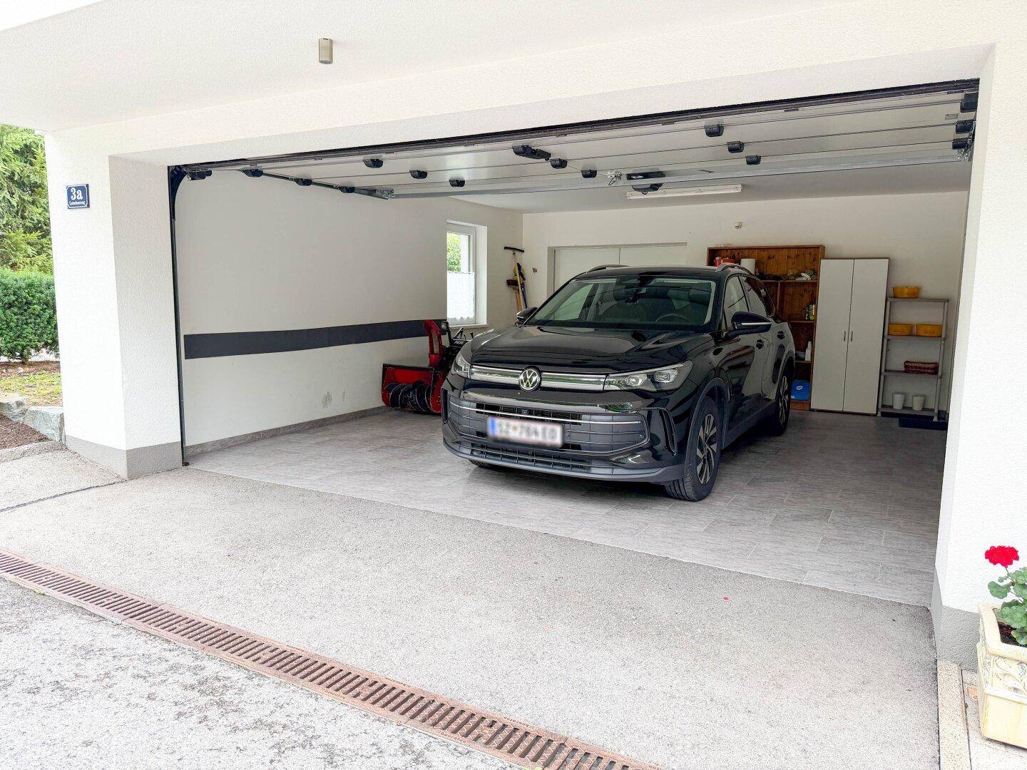 Geräumige Garage mit einem geparkten Auto und Stauraum an den Wänden.