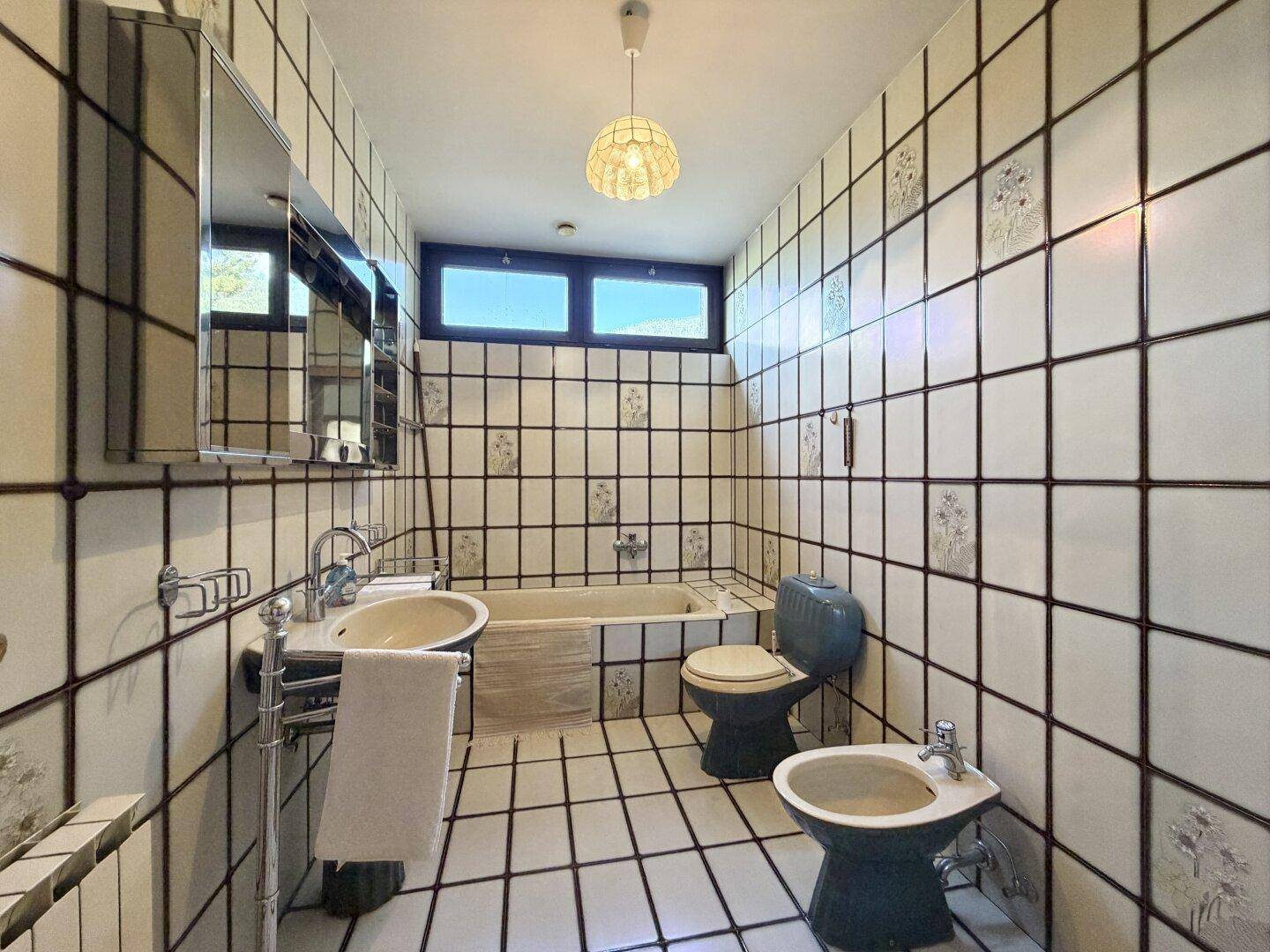 Badezimmer mit Badewanne, WC, Bidet und auffälligen Fliesen im Retro-Stil.