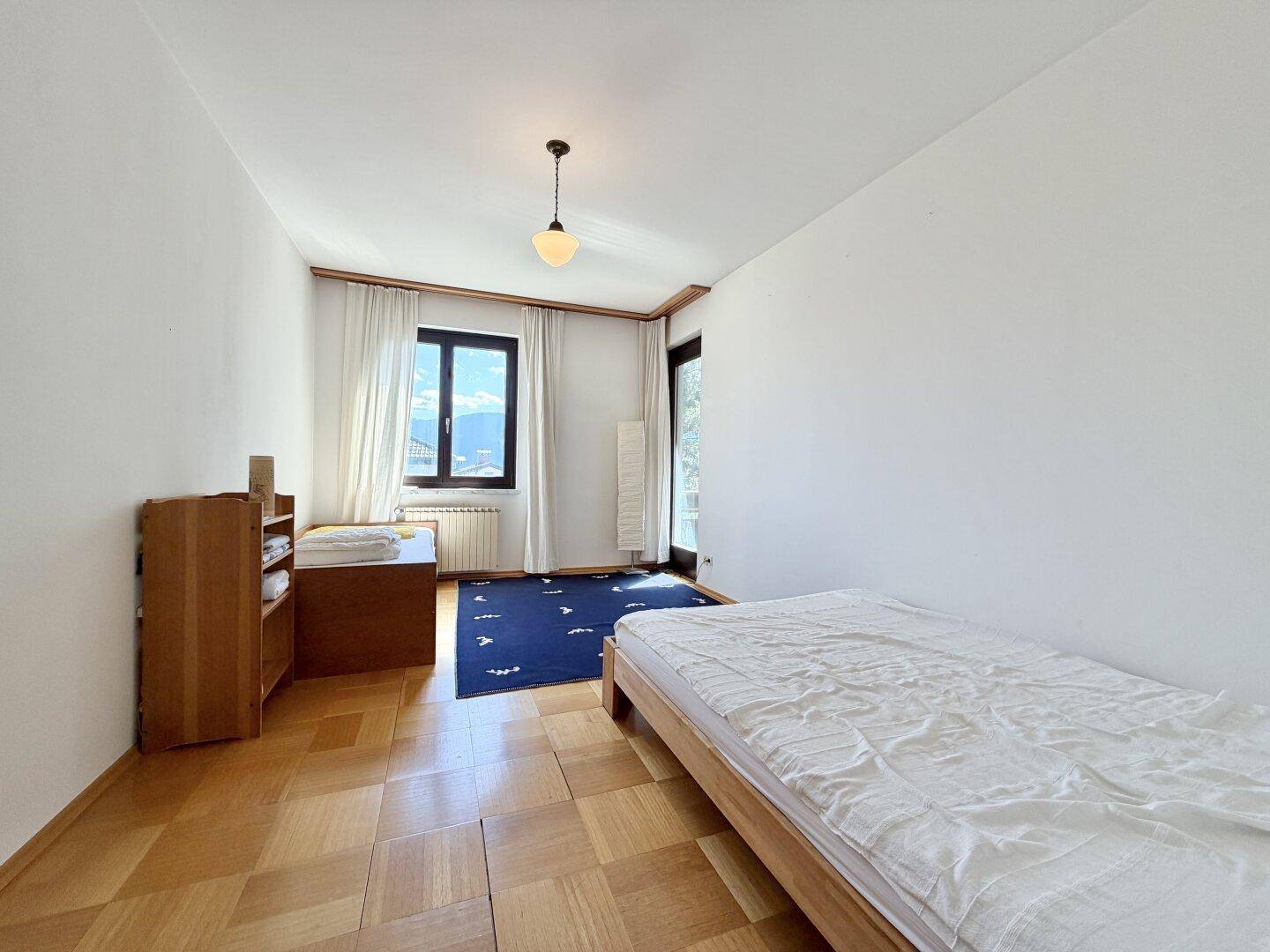 Schlafzimmer mit Holzboden, Einzelbett und Zugang zu einem Balkon mit Bergblick.