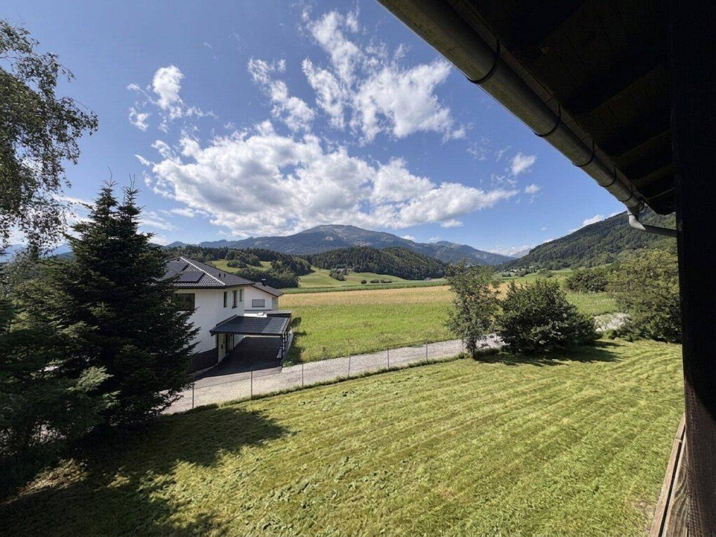 Weitläufiger Blick über grüne Wiesen und Berge von der Immobilie aus.